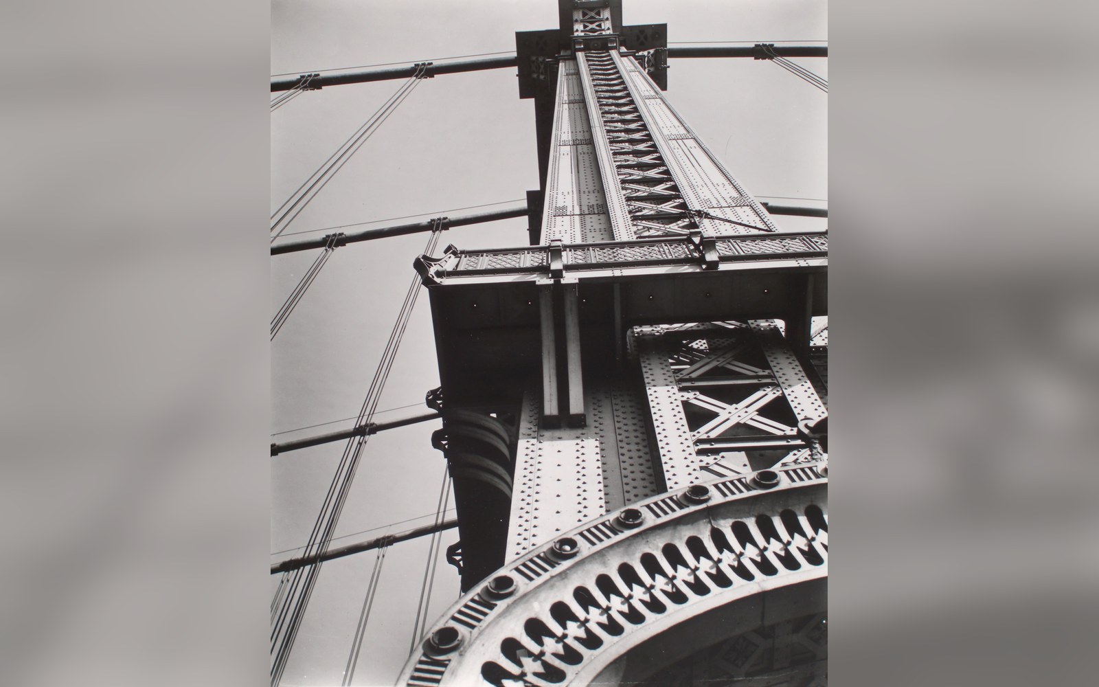 A bridge cable and stay wires seen from directly beneath, stone tower above